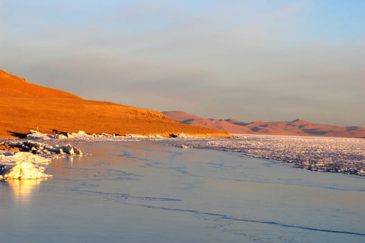 View of golden lakeside at sunrise in Tibet