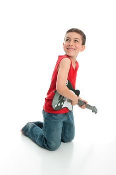 A young 6 year old boy playing guitar and smiling.  White background.