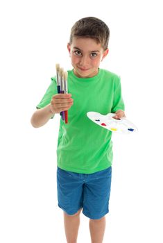 A young smiling boy holding paint brushes and acrylic paints on a palette.  White background.