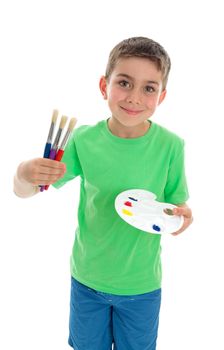 A young boy holding three paintbrushes and an artist palette with acrylic paints.  White Background.