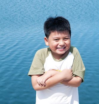 Portrait of a cute young boy smiling against blue sea background