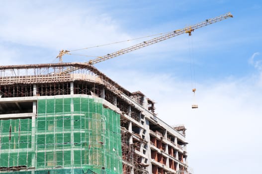 Buildings under construction with crane against blue sky.