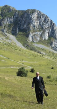 Businessman walking in a mountaineous area.
