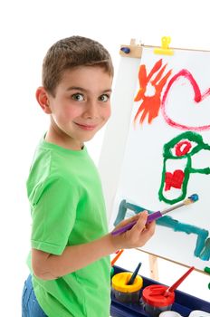 A young schoolboy painting a picture on an art easel.