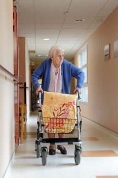 senior woman pushing a walking frame in a  retirement facility