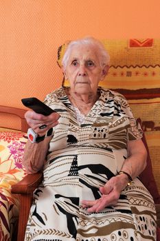 Senior woman changing the TV channel with a remote control