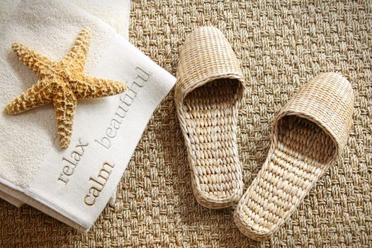 Spa slippers on seagrass carpet with towels and starfish