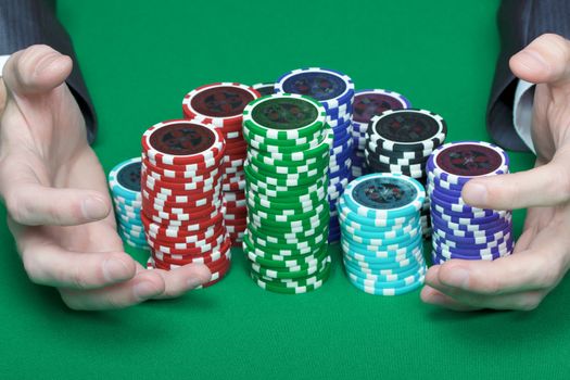 man with two hands rakes the pile of poker chips
