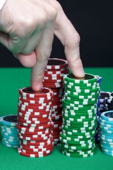 Men's fingers are marching up the pile of playing chips
