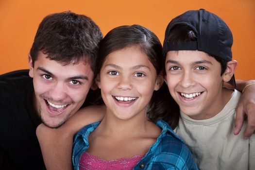 Two caring brothers with sister smiling on orange background 