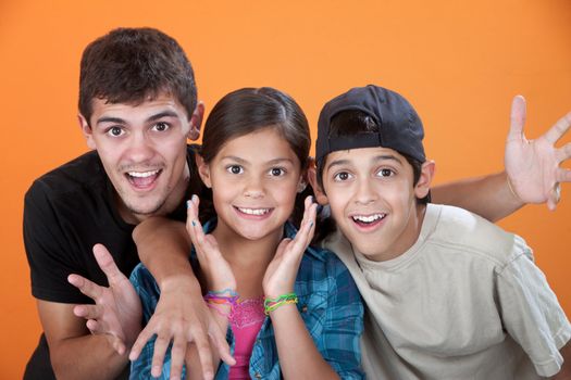 Surprised Siblings with Big Brother on orange background
