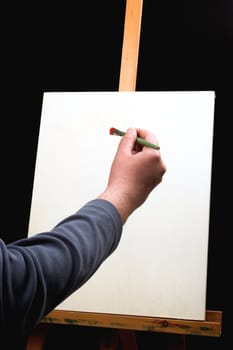 canvas,hand with brush and easel in black background
