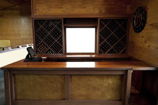 A empty wooden bar with wine bottles in the back