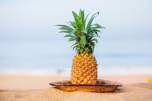 Pineapple on the leaves plate on the sand shore