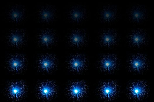 Twenty small illuminated blue fibre optic lamps in horizontal line formations with each line fading progressively towards the top of the image. Black background.