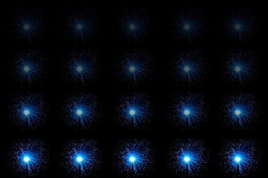 Twenty small illuminated blue fibre optic lamps in horizontal line formations with each line fading progressively towards the top of the image. Black background.