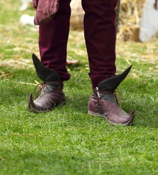 Close-up of specific medieval shoes (long toed shoes) on grass during a medieval festival. They have leather soles and multilayered leather heel made of specially hardened leather.They were popular in 12th-13th centuries in Europe.