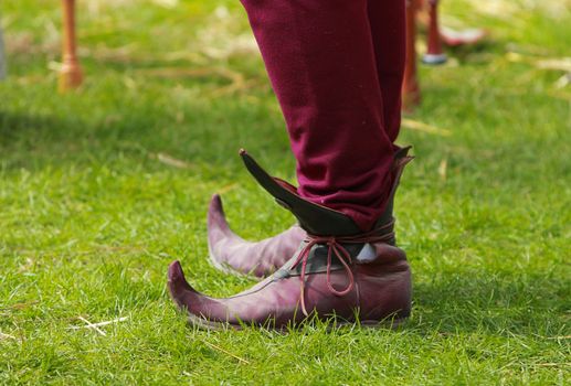 Close-up of specific medieval shoes (long toed shoes) on grass during a medieval festival. They have leather soles and multilayered leather heel made of specially hardened leather.They were popular in 12th-13th centuries in Europe.
