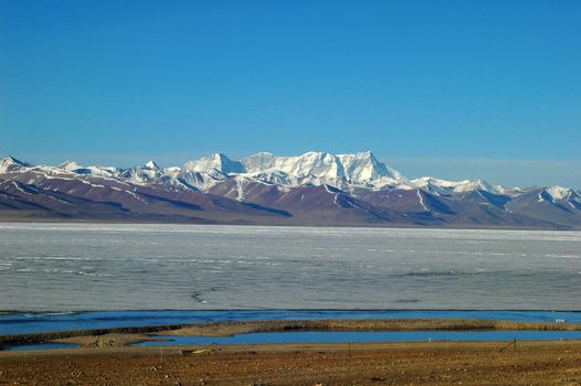 Landscape of snow mountains and frozen lake in the highlands of Tibet in the early spring