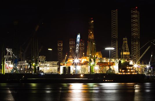 Shiprepair and dock at night - industrial, ships in foreground and drilling platforms in background