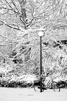 Streetview in the snow with lamp-post and bike in winter - black and white image