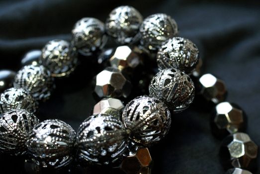 Two bracelets with silver beads over black background, soft focus.