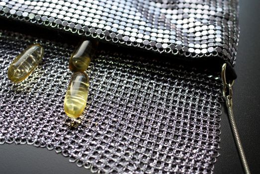 Three omega 3 fish oil capsules coming out of a fancy evening bag; they keep you going.