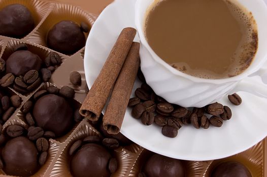 Cup of cappuccino, chocolate pralines, cinnamon sticks and beans