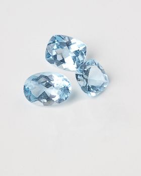 three dirty blue topaz stone against a white background