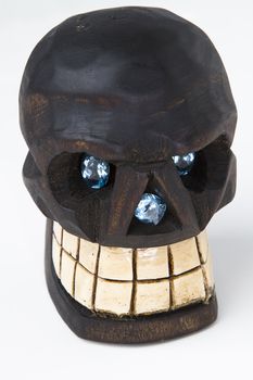 two oval cut blue topaz set as eye and one radiant cut blue topaz set in the nose of a wooden skull