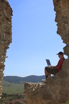 Image of a man working on a laptop outdoors.