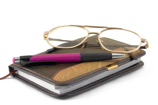 Notebook, pen and glasses on a white background