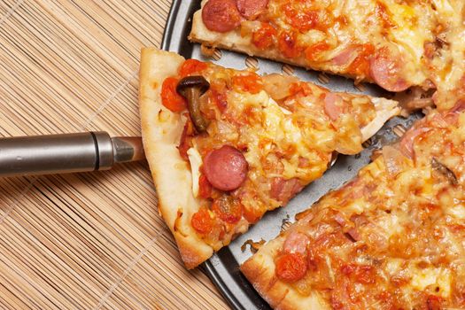 A slice of pizza is lifted from the pan with a spatula