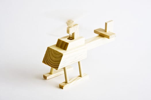 Wooden toy helicopter with spinning propeller on white background