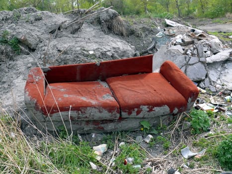 Old red sofa in the dump