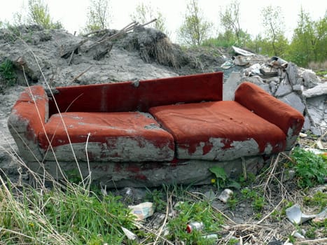 Old red sofa in the dump