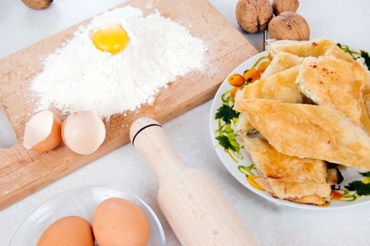 Flour, eggs and othre bakery ingredients on wooden board