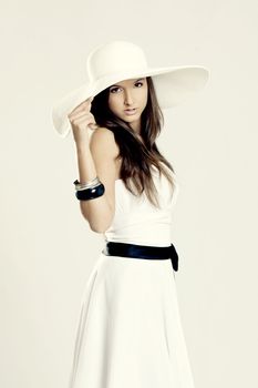 Beautiful and fashion young woman posing and wearing a wonderful white dress with a white hat