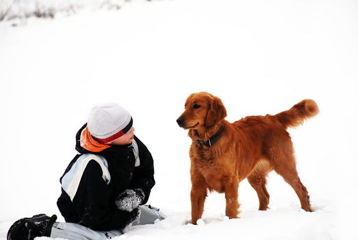 teenage smiling caucasian boy with golden retriever dog outdoor over winter snowy background