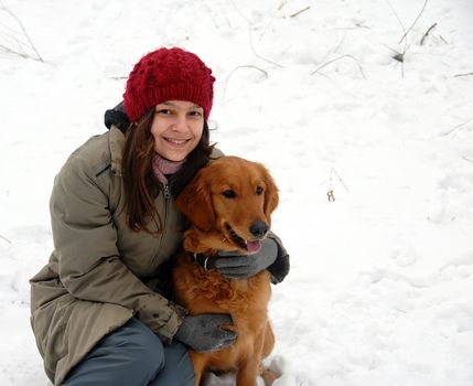 teenage smiling caucasian girl with golden retriever dog outdoor over winter snowy tree