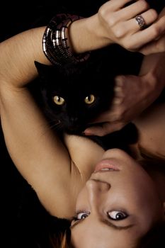 View of a beautiful woman on the bed with a black cat.