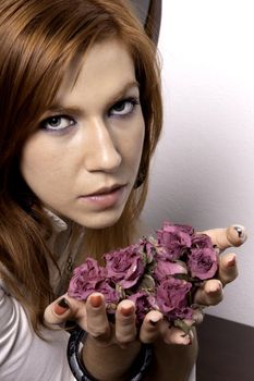 View of a beautiful woman offering a plate full of lifeless roses.