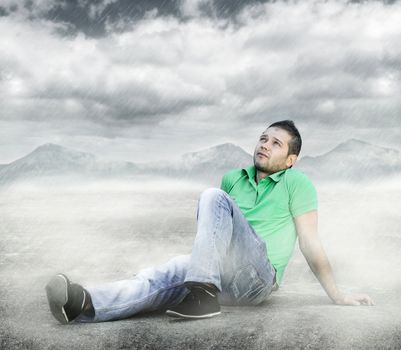 Young man sitting on the ground and looking to the sky