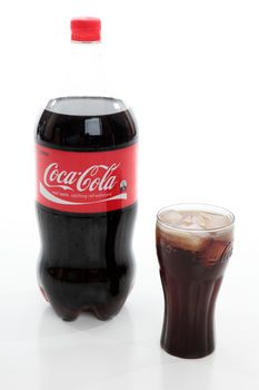 Bottle of Coca-Cola and Coca-Cola glass filled with coca-cola and ice.  Editorial Use Only.  White Background.