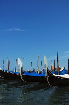 Anchored gondolas in Venetian lagoon with tower in the background