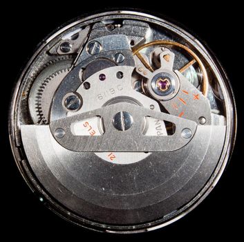 Macro image of the workings of an automatic wristwatch with cogs and polished stainless steel and ruby jewel