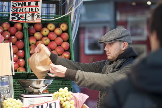 LONDON - FEBRUARY 04: Street vendor wraps up fruits for his customer in Oxford Street, where he competes with large supermarket chains. February 04, 2011 in London, England.