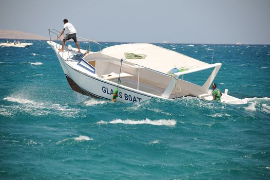 Small boat fighting storm in the blue sea