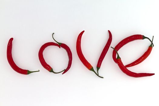 Red hot chili peppers arranged as the word LOVE on white background