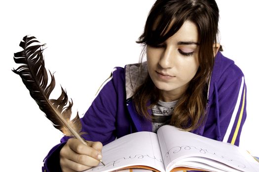 View of a teenager school girl writing on the book with a feather pen.